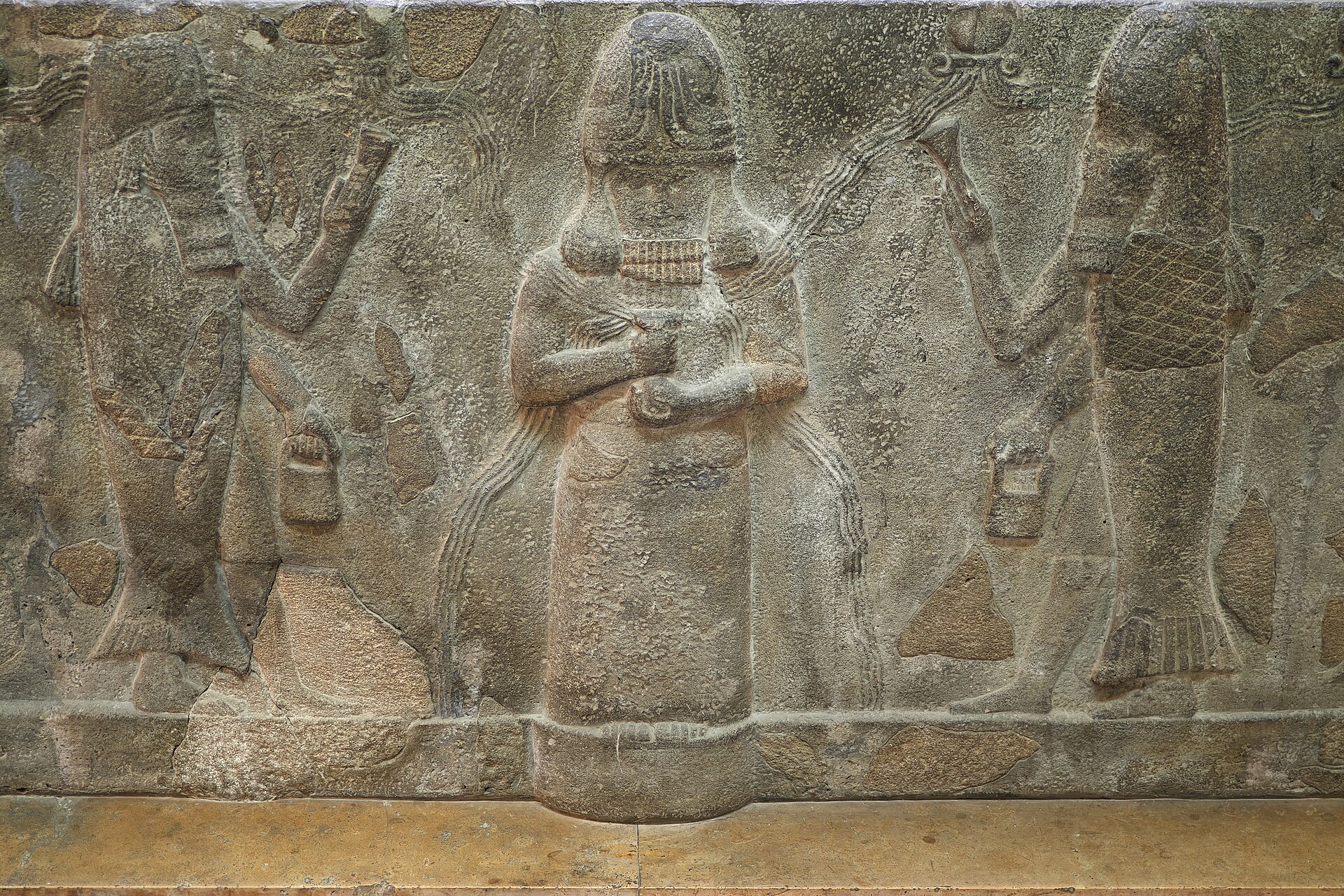 Stone water basin from the temple court at Assur, carved with the god Enki flanked by two apkallu in fish-skin garments, Neo-Assyrian, reign of Sennacherib 704–681 BCE, Pergamon Museum, Berlin