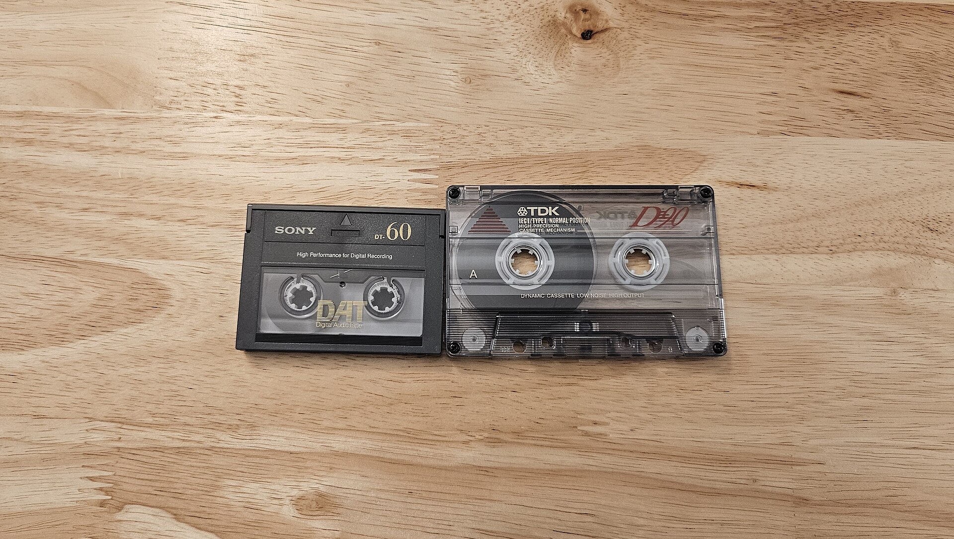 A Compact Cassette audio tape shown beside a DAT cassette, illustrating the magnetic tape format.