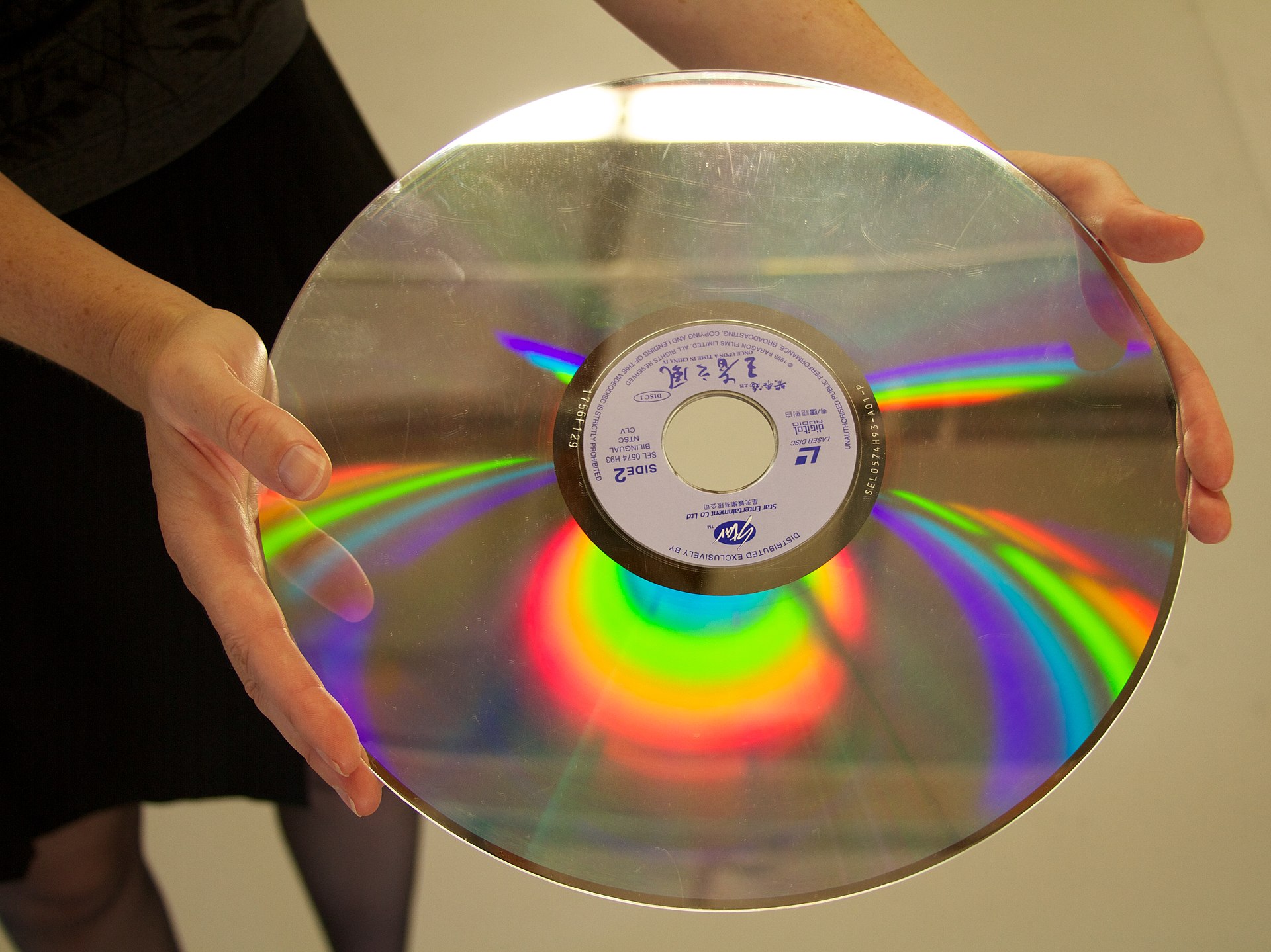 A 12-inch silver LaserDisc optical video disc, far larger than a standard DVD.