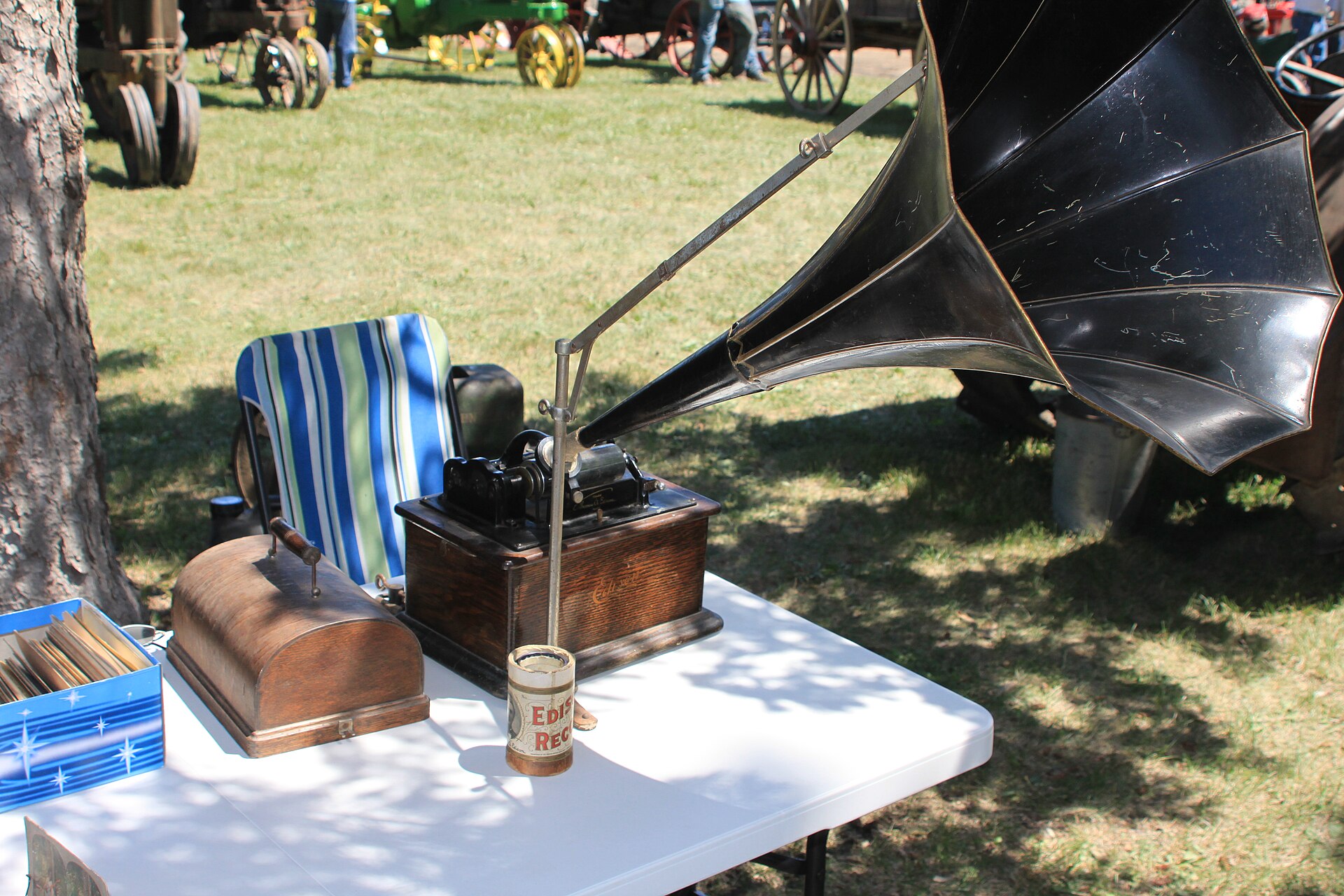 An antique cylinder phonograph with its horn and a wax cylinder on the mandrel.